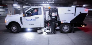 Operator in blue uniform performing a pre-trip inspection on a street sweeper